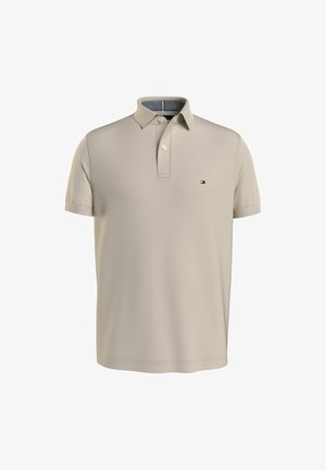 Beige kurzärmeliges Poloshirt mit Zwei-Knopf-Leiste und kleinem Tommy Hilfiger Flaggenlogo auf der linken Brustseite.