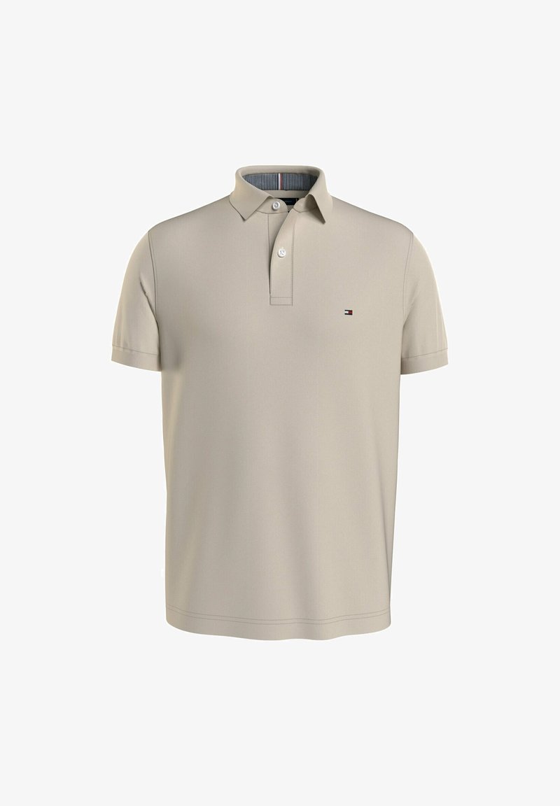Polo beige à manches courtes avec patte à deux boutons et petit logo drapeau Tommy Hilfiger sur la poitrine gauche.