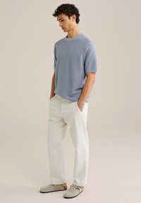 Light blue short-sleeve knit sweater paired with white relaxed-fit trousers and gray slip-on shoes. Simple, textured design with a casual aesthetic.