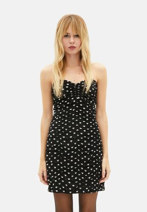 Sort, ærmeløs minikjole med rynket tekstur og hvidt hjerte mønster. Figurformet silhuet, glat materiale og lige kant.