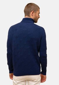 Suéter de punto en navy con cuello alto, que presenta un patrón texturizado y puños acanalados. Acabado suave, material blando y corte relajado.