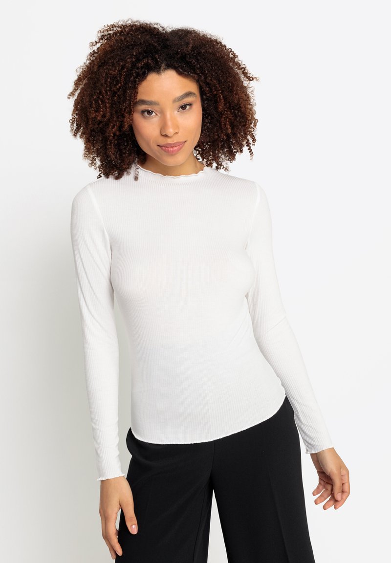 Witte lange mouwen ribbel top met een golfrand en een aansluitend ontwerp, gecombineerd met losse zwarte broek. Soepele textuur.