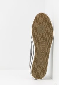 Grå sneakers med en texturerad ovandel, vit gummisula med zickzackmönster och präglad logotyp på undersidan. Stl 42 angiven.