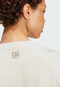 Lichte crème sweatshirt met een klein reliëflogo aan de achterkant van de halslijn. Zachte stof met een ontspannen pasvorm en subtiele textuur.