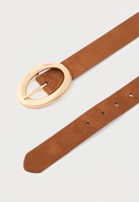 Cinturón de gamuza marrón con cinco agujeros de ajuste y una hebilla ovalada de metal dorado brillante sobre un fondo blanco.