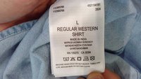 Étiquette de chemise indiquant la taille L, chemise western régulière, fabriquée en Inde, instructions de lavage et symboles d’entretien sur un tissu bleu clair.