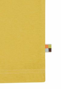 Tessuto di cotone giallo con una trama liscia, caratterizzato da un'etichetta a contrasto con quadrati colorati all'orlo. La cucitura del bordo è visibile.