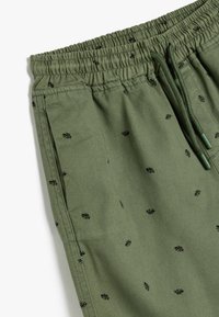 Olijfgroene shorts van katoen, met een trekkoord in de taille en kleine zwarte bladerenpatronen verspreid over het geheel. Glad materiaal met zijzakken.