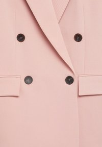 Dvouvrstvý růžový blejzr z texturované látky, s černými knoflíky a dvěma předními kapsami. Hladký povrch s na míru šitým střihem.