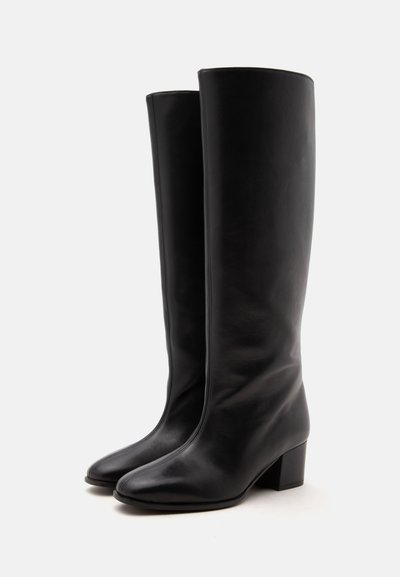 Paire de bottes noires en cuir montant jusqu’au genou avec talons blocs, présentée sur un fond blanc uni.