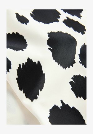 Tessuto con uno sfondo bianco e grandi forme astratte di macchie nere di mucca. Il tessuto appare liscio e leggermente lucido.