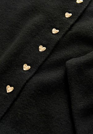 Schwarzer Pullover mit einer Reihe goldfarbener, herzförmiger Knöpfe an der Vorderseite, aus einem weichen, strukturierten Stoff gefertigt.