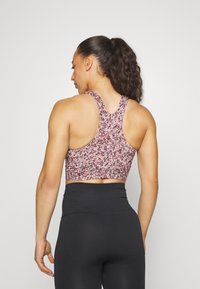 Sutiã desportivo em padrão floral rosa, roxo e preto. Apresenta um design de costas nadador e um comprimento cropped. Tecido suave e elástico.