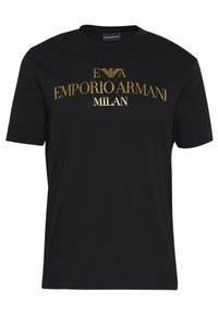 Svart kortärmad T-shirt med guldig text "EMPORIO ARMANI MILAN" och örnlogotyp tryckt på framsidan.