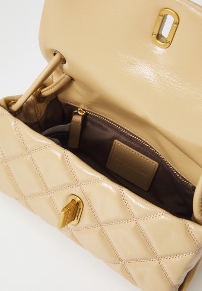 Beige leather handbag with quilted design, gold hardware, and a brown fabric interior. Features a zippered pocket and a logo patch.