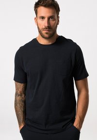 T-shirt in cotone blu navy con maniche corte e scollatura rotonda. Presenta una tasca sul petto e una texture morbida. Design semplice e classico.