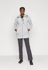 Gray fuzzy jacket with a hood, zip closure, and two pockets. Paired with dark pants and black shoes, against a plain white background.