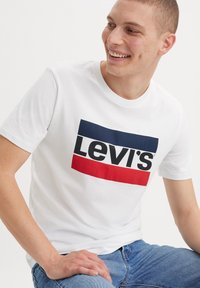 Witte katoenen t-shirt met een rechthoekig Levi's logo in marineblauw en rood, korte mouwen en een ronde hals.