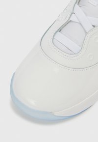 Λευκό δερμάτινο παπούτσι σνίκερ με στρογγυλεμένη μύτη, γλώσσα από δίχτυ και λευκά κορδόνια. Διαφανής γαλάζια σόλα φωτίζει το σχέδιο.