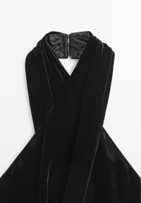 Top da vestito in velluto nero con design a collo all'americana, con spalline incrociate e texture liscia e lucida. Chiusura con fermaglio sul retro.