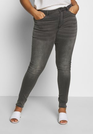 Gray slim-fit jeans with a smooth texture, five-pocket design, and subtle fading. Paired with white open-toe sandals.
