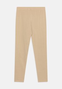 Leggings en coton nude avec un design ajusté, une taille élastique et une texture lisse, s'étendant jusqu'à la cheville sans coutures.