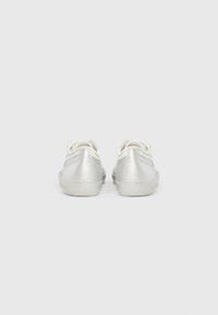 Sølvglitrende sneakers med lavt design, hvite snører og en teksturert overflate. Rund tå og polstrede såler for komfort.