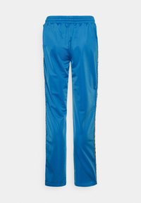 Blå idrottsbyxor gjorda av ett slätt, glänsande material med elastisk midja. Sid sömmarna har svarta och vita detaljer.