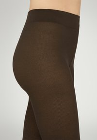 Brune ribbede leggings med en bred talje, der har en glat tekstur og et tætsiddende design, velegnet til afslappede eller lagdelte outfits.