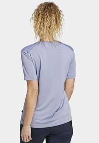 Lichtpaarse sportshirt met korte mouwen, zachte textuur en ronde halslijn. Heeft raglan schouders en een licht gebogen zoom voor extra comfort.