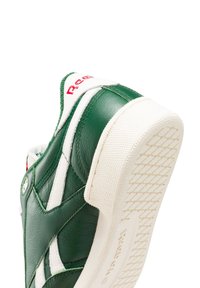 Zöld bőrvászon sneaker fehér részletekkel, texturált gumitalppal és piros logóval. Rétegezett kialakítással rendelkezik varrási részletekkel.