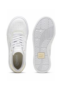 Sneaker bianche con un design perforato, suola testurizzata, lacci piatti e accenti gialli sottili. Logo visibile sul lato e sulla suola.