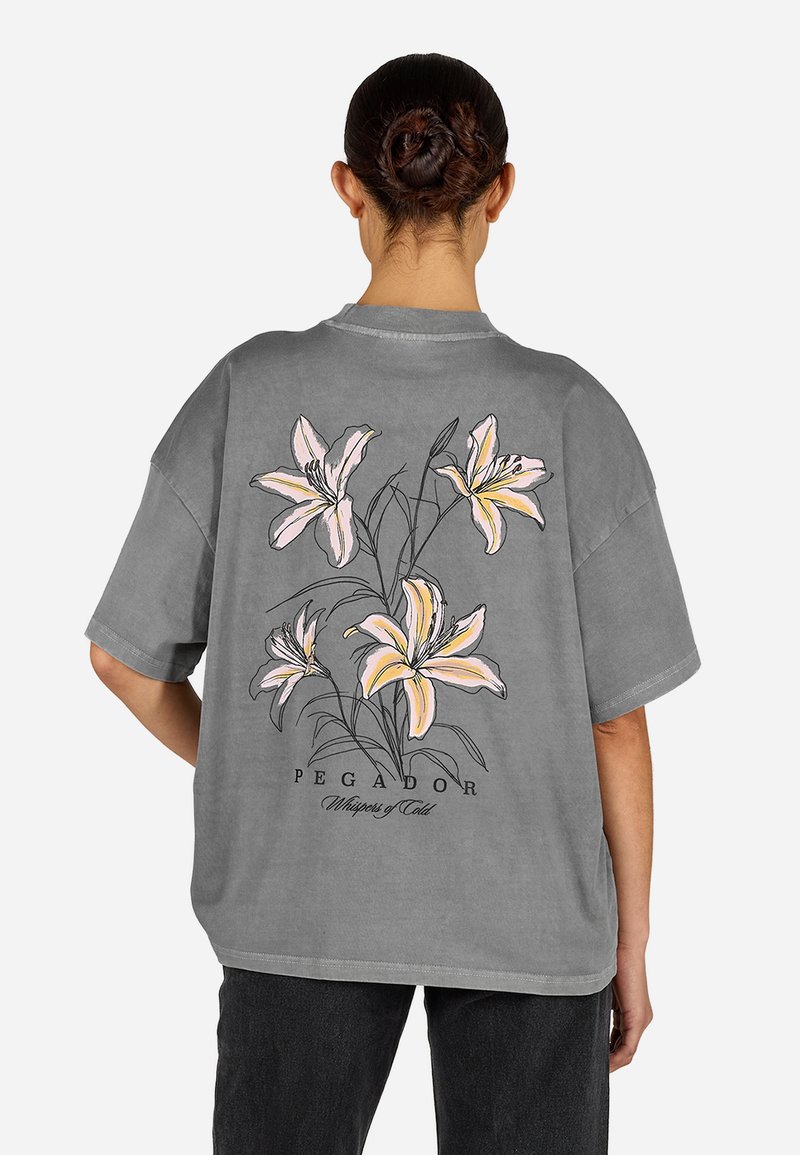 Hallikas üleöö T-särk, millel on lillemuster, kus on roosa liilia ja mustad detailid selja peal. Lühikesed varrukad ja vabalt langev lõige.