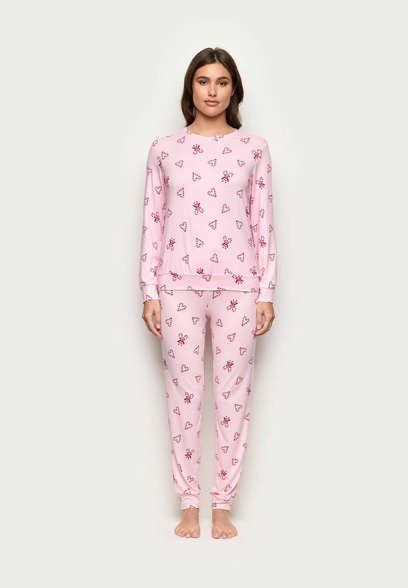 Vaalea vaaleanpunainen pyjama-asuste, jossa on pitkät hihat ja täyspitkät housut, koristeltu pienillä punaisilla tikkukarkeilla ja sydämen kuvilla, valmistettu pehmeästä kankaasta.