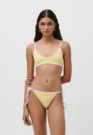 Yellow bikini made of smooth fabric, featuring a triangle top with white trim and adjustable tie-side bottoms. Minimalist design.