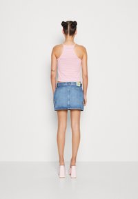 Růžovo-bíle pruhovaný top na ramínka spárovaný s světle modrou džínovou minisukní. Outfit má štítek na zadní straně a růžové boty na blokovém podpatku.