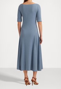 Vaaleansininen, polveen ulottuva mekko, jossa on tiukka yläosa, kolmen neljännesosan hihat ja levenevä helma. Silkkinen kangas, jossa on hienovarainen rakenne.