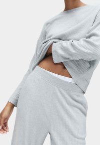 Lichtgrijze geribde sweatshirt met een relaxte pasvorm, gecombineerd met bijpassende geribde broek. De stof lijkt zacht met een subtiele textuur.