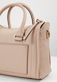 Borsa a mano in pelle rosa con doppie maniglie, superficie testurizzata, accentuazioni in hardware dorato e dettaglio con tasca laterale. Sono visibili i bordi cuciti.