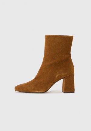 Suede ankle boots in a rich brown color. Features a pointed toe and a chunky, high block heel. Smooth texture without visible hardware.