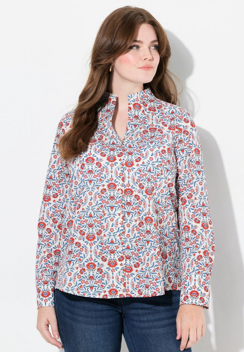 Camisa de manga larga con cuello, en un estampado floral en rojo y azul sobre un fondo blanco, con detalles de botones y un corte relajado.
