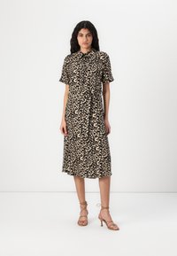 Leopardmönstrad midi-klänning med korta ärmar, knappstängning och knytmidja. Buren med strapsandaler i beige mot en enhetlig bakgrund.