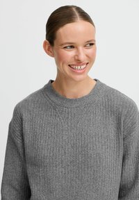 Maglione grigio a costine con scollatura tonda e maniche lunghe. Tessuto morbido con vestibilità rilassata, caratterizzato da dettagli di cucitura sottili.