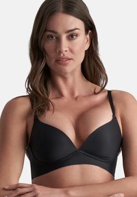 Reggiseno push-up nero realizzato in tessuto liscio, con coppe sagomate, spalline regolabili e un design senza cuciture per un aspetto pulito.