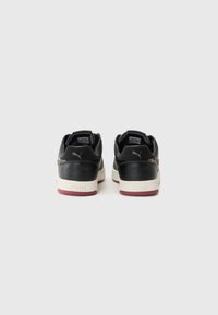 Sneaker in pelle nera con suola beige e dettagli color bordeaux. Presenta una stampa leopardata testurizzata lungo il lato e una linguetta sul tallone.