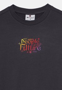 Mørkegrå bomulls-T-skjorte med rund hals, med farget tekst som lyder «we work for the People of the Future» med dekorative detaljer.