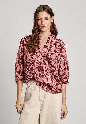 Blusa floreale rosa con scollo a V, parte anteriore arricciata e dettagli con bottoni. Presenta maniche lunghe arrotolate e una vestibilità comoda. Tessuto testurizzato.