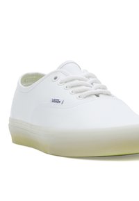 Witte canvas sneakers met ronde neus, vetersluiting en subtiele branding aan de zijkant. Geprofileerde rubberen buitenzool met een semi-transparante afwerking.