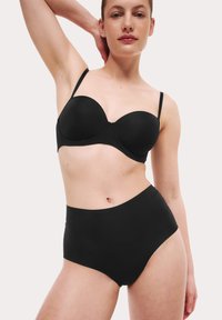 Zwarte beha met gestructureerde cups en verstelbare banden, gecombineerd met zwarte high-waisted slipjes. Gladde textuur, minimalistisch ontwerp.