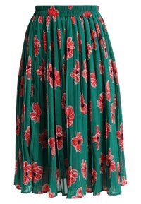Gonna plissettata verde con motivo floreale in rosso e nero. La vita elasticizzata offre elasticità, con una texture leggera e trasparente.